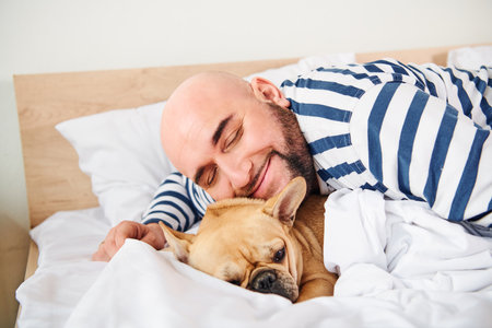 A man and his dog peacefully lie in bed together.の写真素材