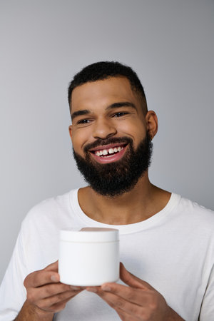 African american handsome man with a beard holding jar of cream.の写真素材