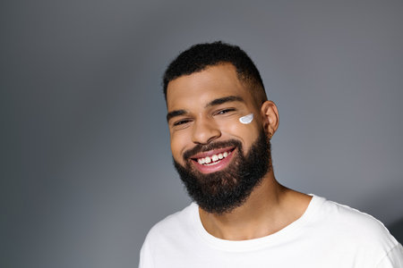Handsome man with beard tending to his skin in a white tee.の写真素材