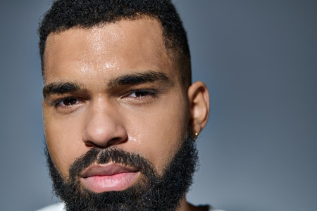 A handsome young man with a beard focusing on his skin care routine.の写真素材