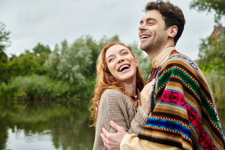 A stylish man and woman stand together in a green park, showcasing their boho style outfits on a romantic date.の写真素材