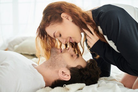 A man and woman relax together on a cozy bed in their bedroom, enjoying a peaceful and intimate...