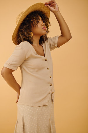 A stunning African American woman, adorned in a dress and hat, exudes grace and style in a studio setting.の写真素材