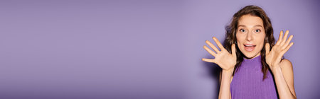 A stylish young woman in a vibrant purple dress with her hands covering her face against a vivid...