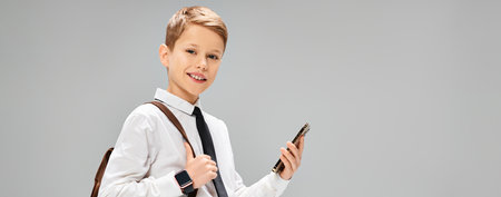 Preadolescent boy in white shirt and tie holding a cell phone, portraying a business concept.の写真素材