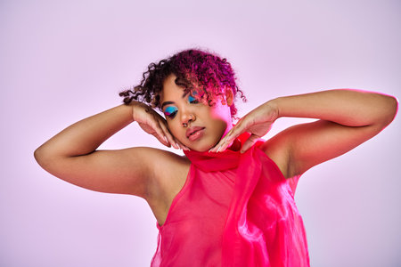 Beautiful African American woman striking a pose in a stylish pink dress against a vibrant backdrop.
