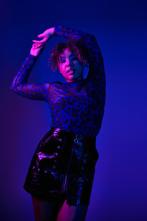 Beautiful African American woman striking a pose in vibrant black and purple attire.