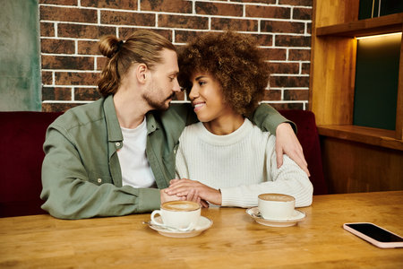A man and woman, both African American, seated at a cafe table enjoying cups of coffee together.の写真素材