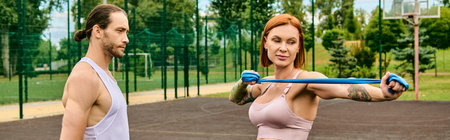 A woman in sportswear stand on a court, while exercising with personal trainer.の写真素材