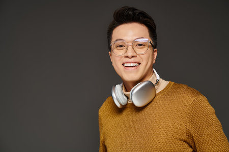A fashionable young man dressed in a sweater, actively listening to music through headphones.の写真素材