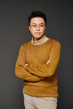 Fashionable young man in glasses and sweater posing confidently in elegant attire.