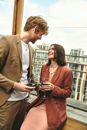 A stylish man stands beside a woman gracefully holding a glass of wineの写真素材