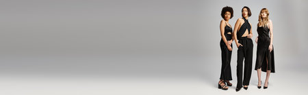 Three diverse women standing together, showcasing beauty and elegance against a grey studio background.の写真素材