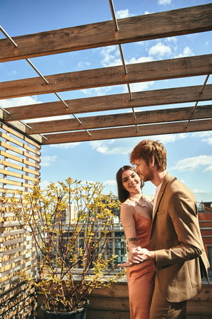 A man and a woman standing on a rooftop, looking out at the city skylineの写真素材