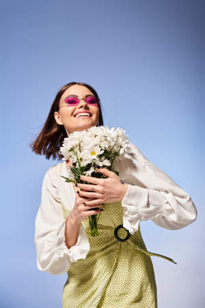 A young woman with brunette hair, elegantly holding a bouquet of flowers in a studio setting.の写真素材