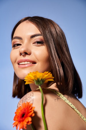 A young woman with brunette hair holding a delicate flower, exuding grace and elegance.の写真素材