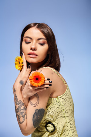 A young brunette woman gracefully holds a delicate flower in a studio setting.の写真素材
