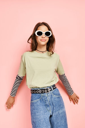 A stylish teenage girl in a green shirt striking a pose with sunglasses on, exuding confidence and...