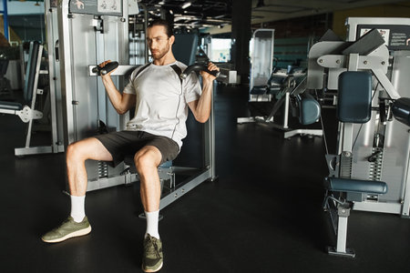 An athletic man in active wear sitting on a gym bench, holding handles on exercise machine