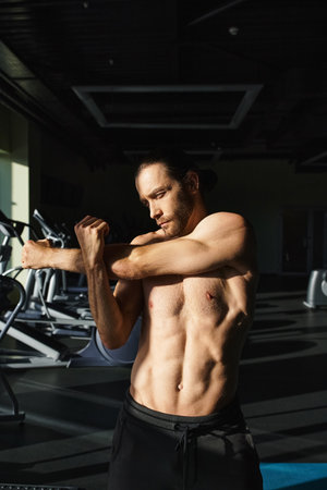 A shirtless muscular man flexing his muscles in a gym, showcasing his strength and dedication to...