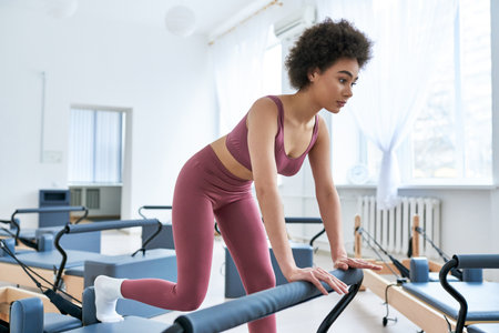 A woman in a pink sports bra top and pink leggings stands gracefully.の写真素材