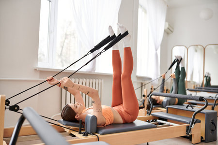 Beautiful woman gracefully performs exercises during a pilates lesson.の写真素材