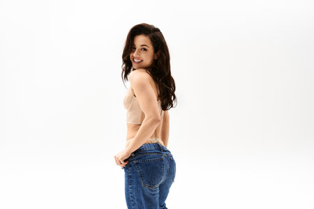 Stylish woman in tan top and jeans strikes a pose.
