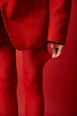 A young woman in a red suit and red tights strides confidently against a vibrant background in a studio.の写真素材
