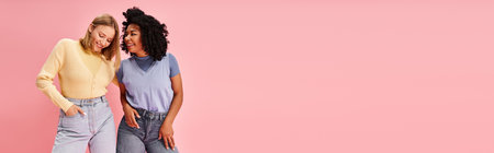 Two attractive diverse women in casual attire stand together against a vibrant pink background.の写真素材