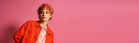 A woman with red hair poses in front of a pink wall.の写真素材