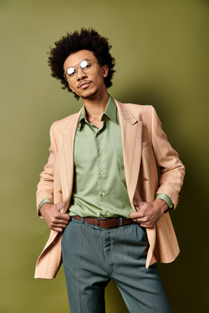Stylish African American man in suit and sunglasses confidently poses against a green background.の写真素材