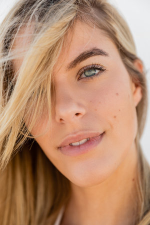 A young, beautiful blonde woman on Miami Beach showcasing her long, flowing hair under the bright sunlight.の写真素材
