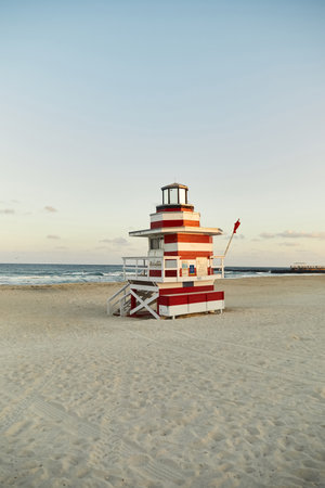 A red and white lifeguard stand stands tall on a sandy beach in Miami, Florida.の写真素材