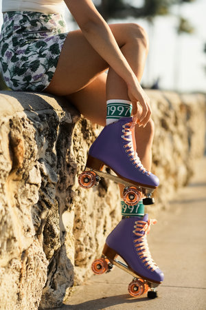 A young woman adjusts her purple roller skates, preparing to cruise the streets of Miami.