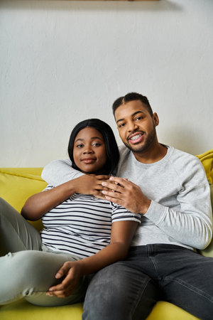 A loving African American couple relaxes on a yellow couch at home.の写真素材