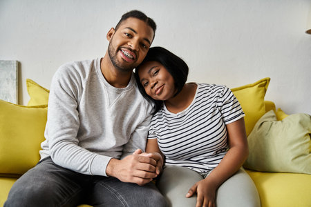 A loving African American couple relaxes at home, sharing a cozy moment together on the couch.の写真素材