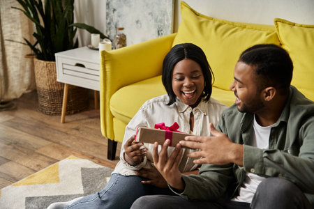 A happy African American couple exchanging a gift at home.の写真素材