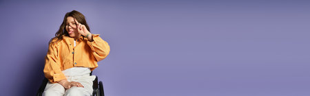 A young woman in a wheelchair smiles brightly, her hand raised in a peace sign, in front of a lavender backdrop.の写真素材