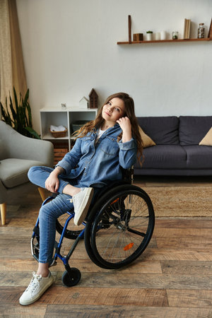 A young woman in a wheelchair sits in a modern apartment, looking relaxed and confident.の写真素材