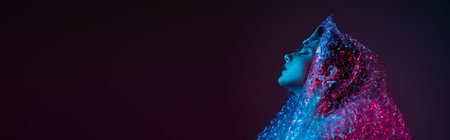 A woman's face glows under a vibrant blue and pink light, covered in a bubble wrap-like material.の写真素材