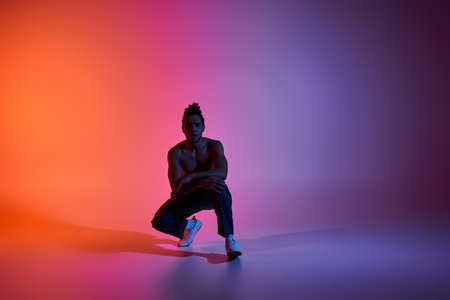 A young African American man dances in a studio with vibrant neon lighting.
