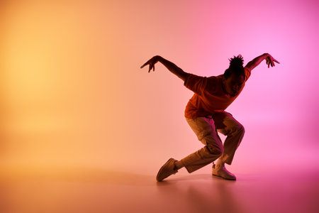 A young African American man dances on a colorful gradient background, showcasing his skill and passion for movement.の写真素材