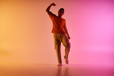 A young African American man dances in front of a vibrant gradient background, showcasing his energy and passion for dance.の写真素材