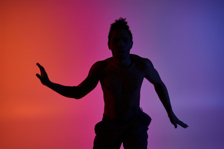 A silhouette of a young African American man dancing against a colorful gradient background.の写真素材