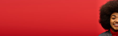 A woman with a large afro hairstyle standing against a vivid red background.の写真素材