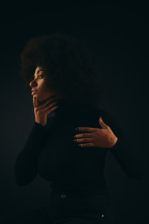 Stylish African American woman with hands on chest in trendy attire against vibrant backdrop.