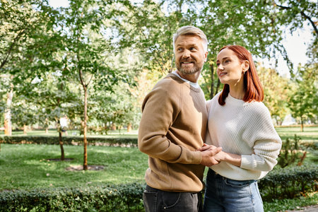 A couple in casual clothing stands together in a park, enjoying a leisurely stroll.の写真素材