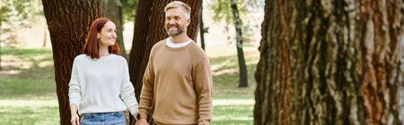 A man and a woman walk hand in hand through a lush forest.の写真素材