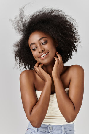 A beautiful young African American woman gracefully poses with her curly hair billowing in the wind.の写真素材