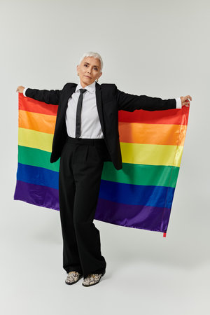 A mature woman proudly displays a rainbow flag with elegance.